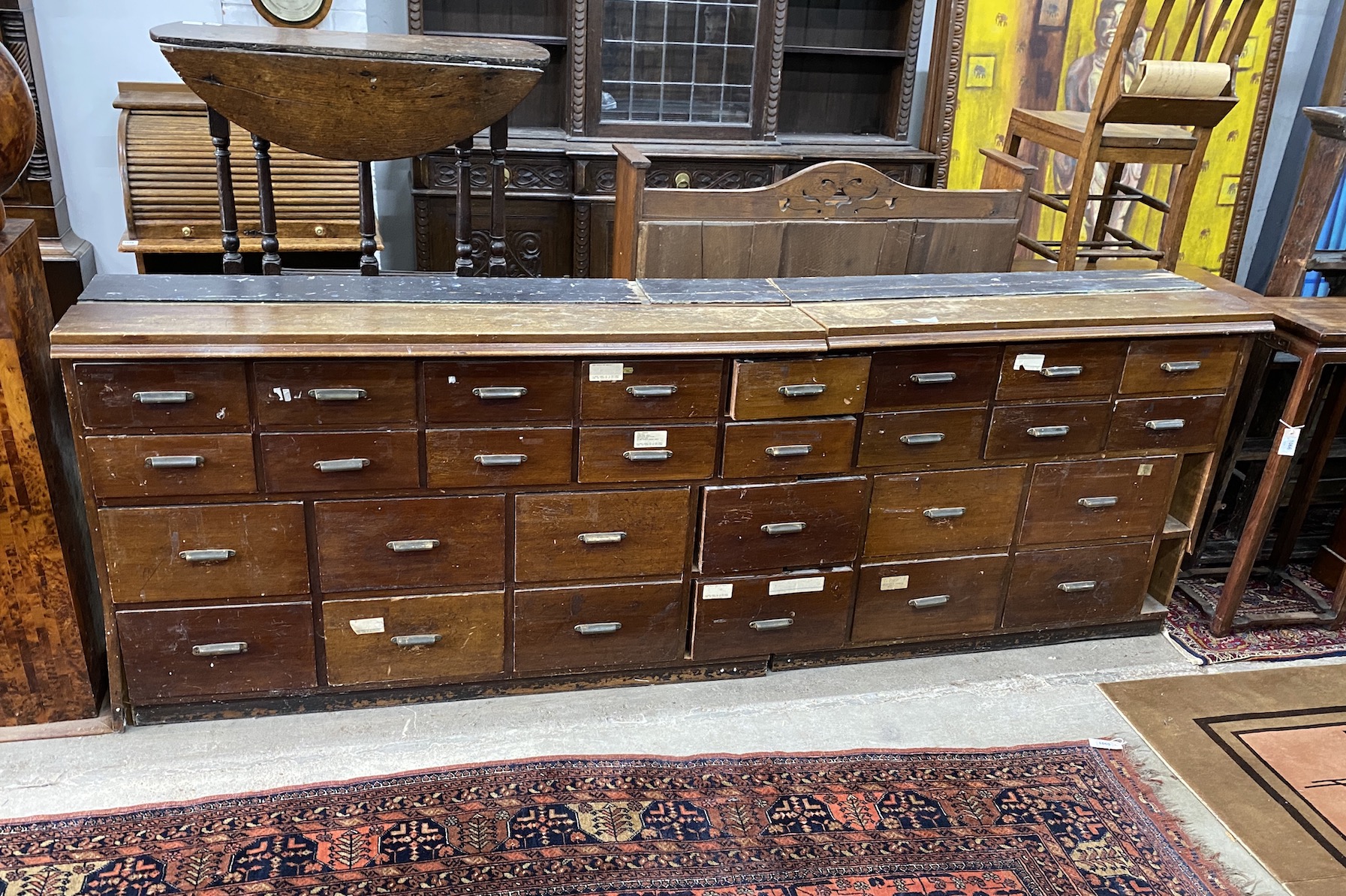 An apothecary bank of twenty eight drawers, now in two sections, length 260cm, depth 41cm, height 91cm